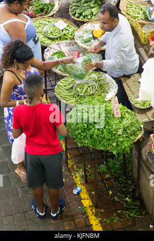 Kunden, die Gemüse an einem Marktstand auf dem Zentralmarkt in Port Louis, Mauritius, Afrika kaufen. Stockfoto