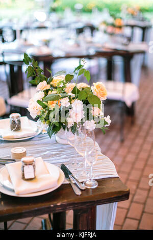 Essen, Kultur, dekorieren Konzept. Bündel aus Vollkommenen Schönen Rosen in verschiedenen Farben auf dem Tisch platziert in der Nähe von Garden Restaurant mit Angeboten für Feier, Teller und Besteck Stockfoto