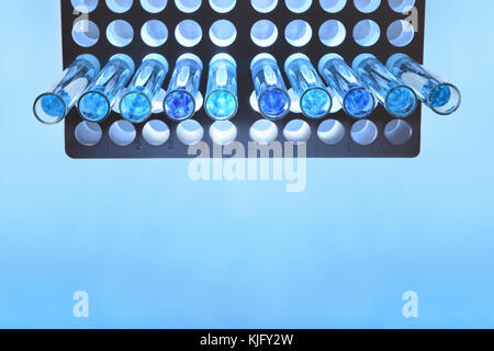 Rohre mit blauer Flüssigkeit auf reagenzglasständer auf blauen Tabelle. Ansicht von oben Stockfoto