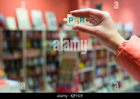 Frau halten puzzle Wort pr in der Buchhandlung. Stockfoto