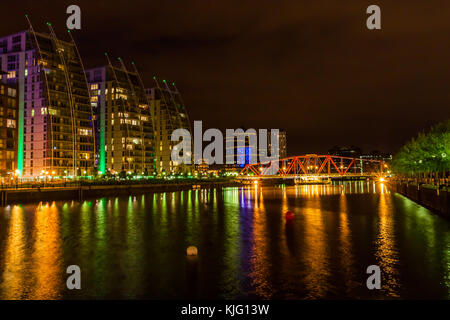 Die Huronen Becken an Salford Quays mit der NV Apartment Gebäude und Swing Bridge leuchtet gegen den Nachthimmel. Stockfoto