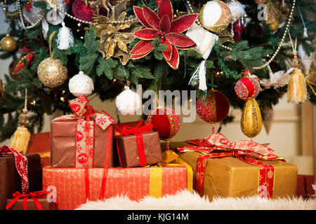 Helles Studio geschossen von geschenkboxen vor einem herrlichen üppigen Weihnachtsbaum, in Rot und Gold Stockfoto