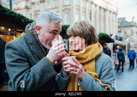 Reifes Paar trinken heiße Getränke in einer Stadt Weihnachtsmarkt. Stockfoto