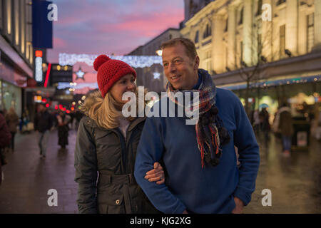 Reifes Paar sind, genießen Sie einen Abend in der Weihnachtszeit durch die Stadt schlendern. Stockfoto