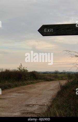 Holz- Ausfahrt in der Dämmerung mit Schmutz Straße, die in die Ferne links Stockfoto