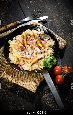 Bratpfanne von Finger-förmige Kartoffel Knödel mit Sauerkraut und Speck auf Jute Stockfoto