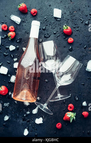 Rosé Wein mit Eiswürfeln und Früchte wie Aroma Symbole auf dunklem Hintergrund Stockfoto