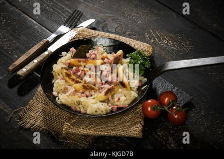 Bratpfanne von Finger-förmige Kartoffel Knödel mit Sauerkraut und Speck auf Jute Stockfoto