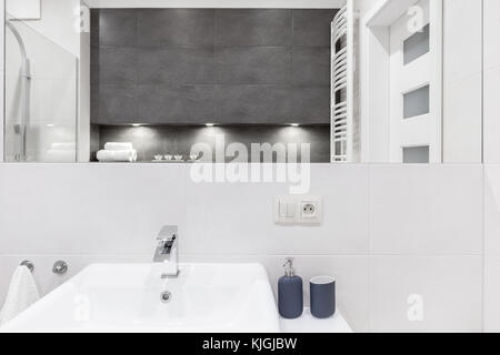 Modernes Badezimmer mit grauen und weißen Fliesen. Es gibt einen großen