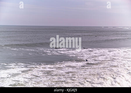 Surfer in der Nordsee an saltburn am Meer in North Riding von Yorkshire an einem Wintertag, die Wellen surfen. Stockfoto