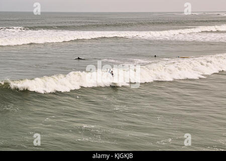 Surfer in der Nordsee an saltburn am Meer in North Riding von Yorkshire an einem Wintertag, die Wellen surfen. Stockfoto