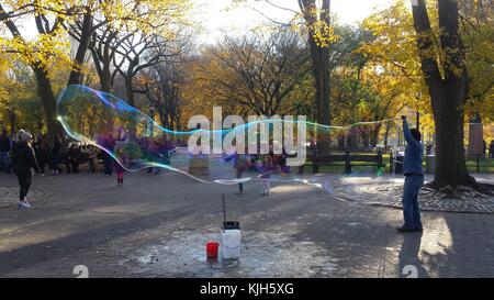 New York, Vereinigte Staaten. 24 Nov, 2017. Ein Mann bläst große Blasen im New Yorker Central Park als Kinder und Schaulustige beobachten, an einem schönen Herbsttag, 24. November 2017 Credit: Adam Stoltman/Alamy leben Nachrichten Stockfoto