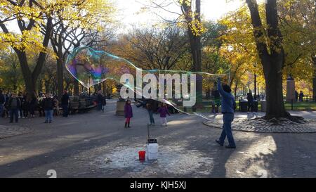 New York, Vereinigte Staaten. 24 Nov, 2017. Ein Mann bläst große Blasen im New Yorker Central Park als Kinder und Schaulustige beobachten, an einem schönen Herbsttag, 24. November 2017 Credit: Adam Stoltman/Alamy leben Nachrichten Stockfoto