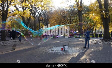 New York, Vereinigte Staaten. 24 Nov, 2017. Ein Mann bläst große Blasen im New Yorker Central Park als Kinder und Schaulustige beobachten, an einem schönen Herbsttag, 24. November 2017 Credit: Adam Stoltman/Alamy leben Nachrichten Stockfoto