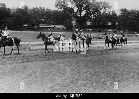 Ein Foto von Rennpferden an den Start vor dem Start des Rennens vorgeführt werden, sind die Menschen im Infield versammelt, Autos können gesehen werden entlang der Gebäude im Hintergrund, Lancaster, Ohio, 1938 geparkt. Von der New York Public Library. Stockfoto