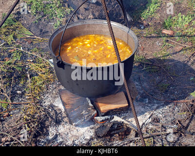 Fischsuppe mit Lachs und Gemüse Kochen im Kessel auf Lagerfeuer Stockfoto
