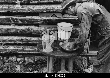 Schwarz-weiß-Fotografie eines Mannes, der seine Hände in einer provisorischen Waschstation in einem Besetzerlager wäscht, von Ben Shahn, gebürtiger Litauer, US-amerikanischer Künstler, der für seine Arbeit für die Farm Security Administration bekannt ist, die die Auswirkungen der Großen Depression in Ozarks, Arkansas, 1935 dokumentiert. Aus der New York Public Library. Stockfoto