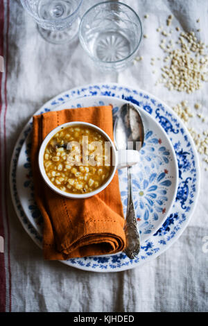 Kürbis, Pilze und Gerste Suppe in einer weißen Schüssel auf einen hölzernen Tisch. Stockfoto