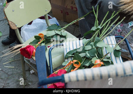 Ein Strauß roter Rosen mit katalanischen Flagge Bänder ruhen auf den Lehrstuhl für ein blumengeschäft Stall bereit während der Sant Jordi feiern in Barcelona verkauft zu werden. Stockfoto