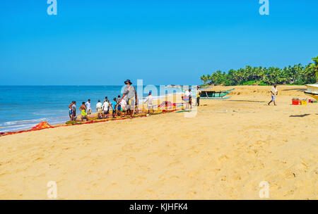 Bentota, Sri Lanka - Dezember 6, 2016: Die malerischen tropischen Strand mit einer Gruppe von Fischern, stehend auf der Seine mit einem Catch, am 6. Dezember in Bento Stockfoto