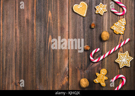 Weihnachten Zuckerstangen, Lebkuchen in verschiedenen Formen, Haselnüsse, Walnüsse auf einem braunen Holztisch. Kopieren Sie Platz Stockfoto