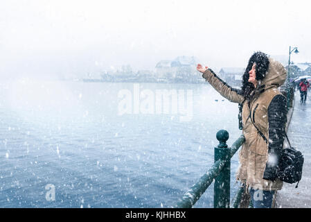 Winter Reiseziele Thema Bild mit einer Frau, die auf dem Hallstätter See, Schneeflocken und Genießen der Schneefall, in Hallstatt Stadt Stockfoto