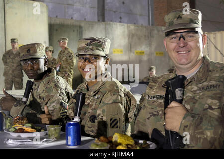 FLUGPLATZ BAGRAM, Afghanistan - von links, Sgt. 1. Klasse Robert Roseboro, der nicht in Betrieb genommene Offizier, Sgt. Petrene Caldwell, ein nicht beauftragter Officer von Future Operations, und Sgt. Nicolaas Van Tonder, ein nicht beauftragter Offizier von Future Operations, der alle Teil der 3. Infanterie-Division Resolute Support Sustainment Brigade ist, isst am 13. November im Bagram Airfield, Afghanistan, zu Abend. Die Soldaten genossen Live-Musik, eine Begrüßungsrede von Major General Leopoldo Quintas, dem Kommandeur der 3. Infanterie-Division und ein Abendessen bei der Zeremonie. (USA Armeephot Stockfoto