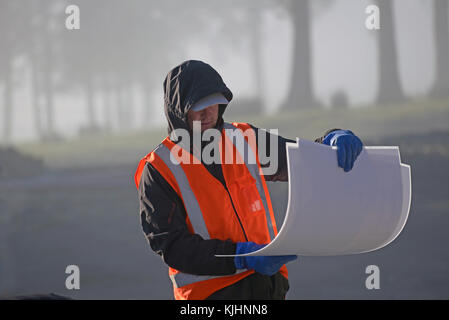 Greymouth, Neuseeland, 17. AUGUST 2014: Ein nicht identifizierter Builder prüft seine Pläne an einem frostigen Morgen in der Nähe von Greymouth, Neuseeland Stockfoto