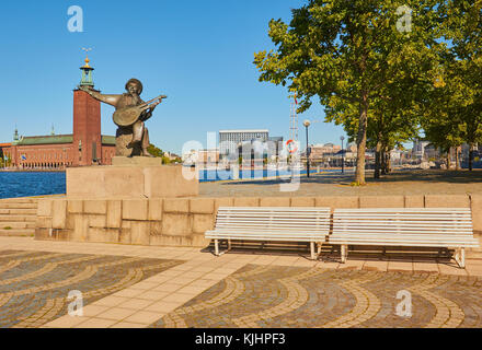 Statue von Evert Taube vor allem Troubadour der Schwedischen Ballade Tradition mit Stadshuset (Rathaus) im Hintergrund, Riddarholmen, Stockholm, Schweden Stockfoto