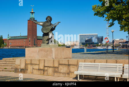 Statue von Evert Taube vor allem Troubadour der Schwedischen Ballade Tradition mit Stadshuset (Rathaus) im Hintergrund, Riddarholmen, Stockholm, Schweden Stockfoto