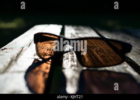 Sonnenbrille auf einer Parkbank an einem sonnigen Tag. Stockfoto