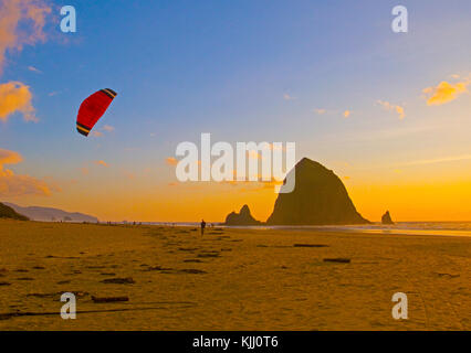 Drachen Flieger auf Cannon Beach mit Haystack Rock bei Sonnenuntergang auf Oregon Küste. Stockfoto