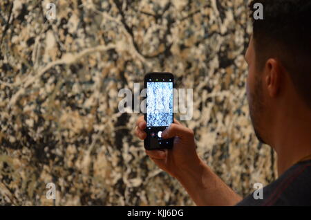 Mann Foto auf Handys von Jackson Pollock Malerei, "Ein: Nummer 31, 1950" im Museum für Moderne Kunst in New York City. Stockfoto