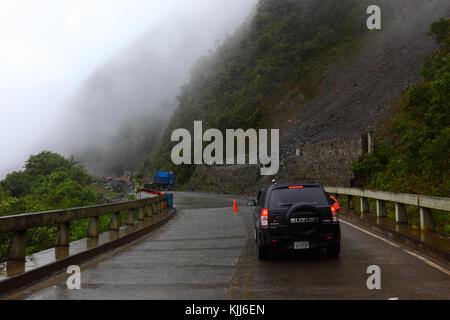 Straßenarbeiter räumen einen kleinen Erdrutsch von der Straße La Paz - Santa Barbara in der Regenzeit, Region Yungas, Bolivien Stockfoto