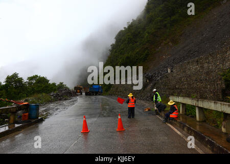 Straßenarbeiter räumen einen kleinen Erdrutsch von der Straße La Paz - Santa Barbara in der Regenzeit, Region Yungas, Bolivien Stockfoto