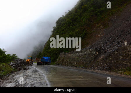 Straßenarbeiter räumen einen kleinen Erdrutsch von der Straße La Paz - Santa Barbara in der Regenzeit, Region Yungas, Bolivien Stockfoto