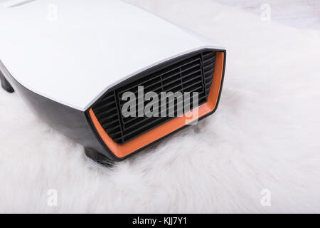 Elektrische Heizung auf weißen, flauschigen Teppich. Winter Hintergrund. Stockfoto