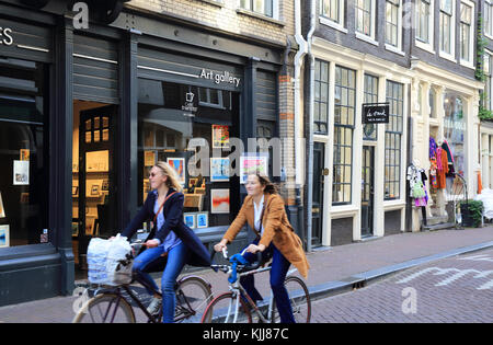 Freunde Radfahren entlang trendy Wolvenstraat, in De 9 Straatjes, die Neun Straßen, in Amsterdam, in den Niederlanden Stockfoto