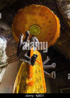 Acht bewaffnete Buddha in Angkor Wat, Kambodscha. acht bewaffnete Buddha Statue in orange Kleidung mit Regenschirm drapiert, in einem Schrein, Angkor Wat, Kambodscha. Die e Stockfoto