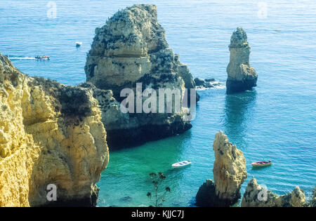 Clifftop Blick auf die Boote segeln durch die markanten Felsformationen an der Küste der Algarve, Portugal. Stockfoto