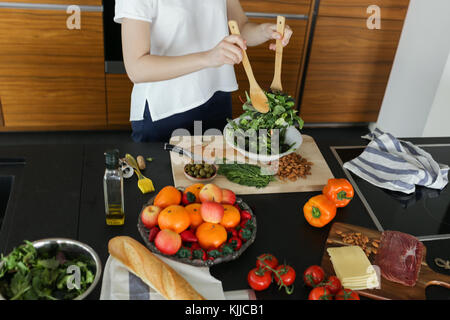 Junge Frau mischen grüner Salat Stockfoto