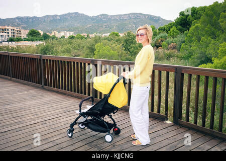 Blondes Haar Frau Bummeln ein Baby im Wagen Stockfoto