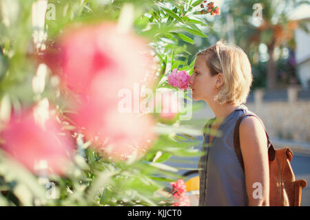 Junge Frau riechenden Duft der Blumen im Freien genießen. Stockfoto