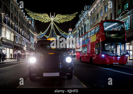 Rote Doppeldecker Bus und Schwarz cabpass unter funkelnden Weihnachtsbeleuchtung entlang der schönsten Einkaufsstraßen der Regent Street. Stockfoto