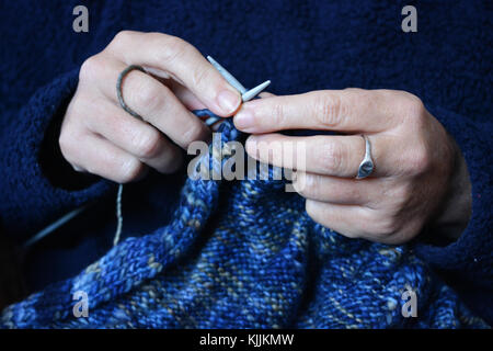 Frau stricken ein blauer Wollpullover, bis der Stricknadeln in die Hand zu schließen. Stockfoto