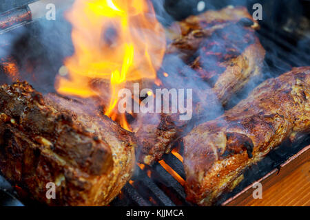 Grillen Baby zurück Rippchen über flammende Grill gegrillte Schweinerippchen Stockfoto