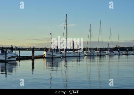 Segel- und Motoryachten günstig entlang der schwimmenden Anlegestelle im Abendlicht. Stockfoto