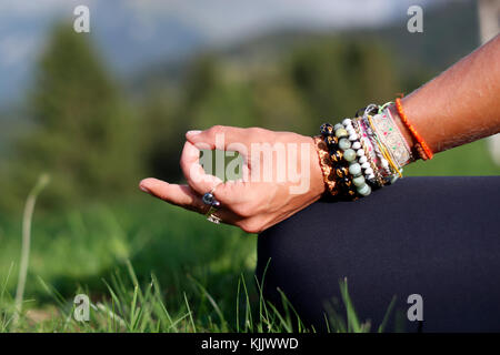 Frau sitzt mit ihren Beinen die Daumen und Hand auf das Knie. Mudra Körperhaltung. Close-up. Frankreich. Stockfoto