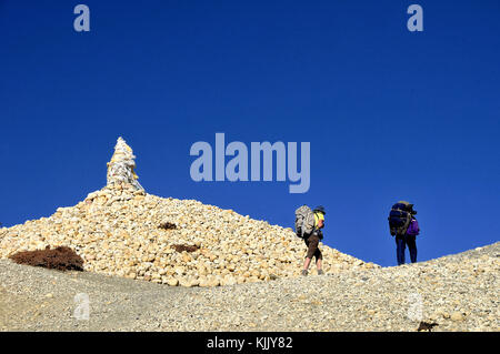 Wanderer zu Fuß hinter einem Cairn an Ghami Pass, Mustang. Nepal. Stockfoto