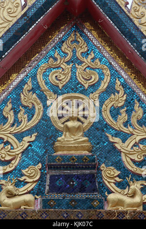 Sitzender Buddha, Dharma Rad- und Rotwild Statuen auf einer Hua Hin Tempel Tympanon. Thailand. Stockfoto